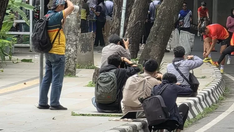 Difoto Tanpa Izin di Tempat Umum? Ini Hak dan Cara Anda Menggugat! 2 Ilustrasi fotografer memotret pelari di ruang publik yang diawasi Komdigi