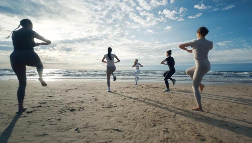 Seorang pelari wanita sedang menggunakan smartwatch untuk berlari di jalur lari outdoor