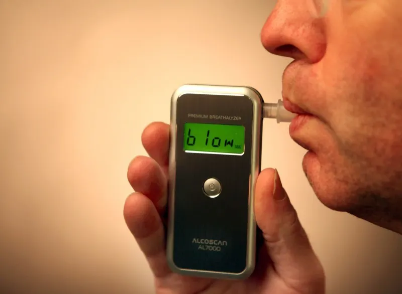 Pengemudi melakukan tes breathalyzer, kontras dengan metode AI